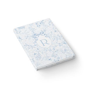 May include: A blue and white floral patterned journal with a monogrammed initial "R" in a crest.