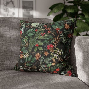 May include: A black throw pillow with a festive holiday pattern featuring green pine branches, red berries, and white snowflakes.