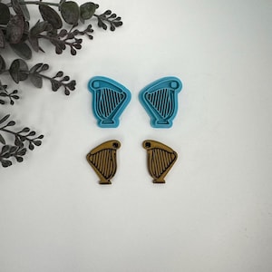May include: Four cookie cutters in the shape of a harp. Two are blue and two are gold.