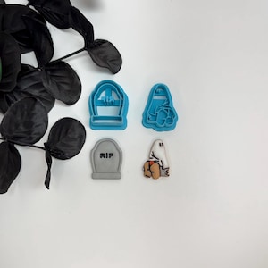 May include: A collection of Halloween-themed cookie cutters and a decorative accent. The cutters include a tombstone with "RIP" text, a ghost, and two other shapes. The accent is a black leafy branch.