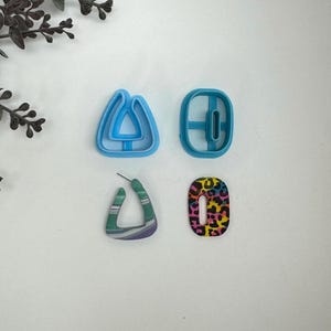 May include: Four pairs of earrings, two blue plastic earring molds, one green and white striped earring, and one multi-colored leopard print earring.