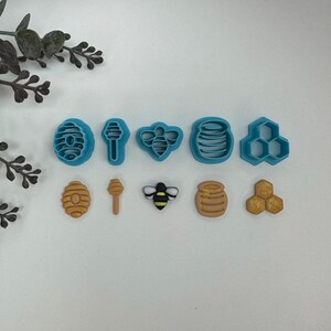 May include: A set of nine blue and brown plastic cookie cutters shaped like honeycombs, honey pots, bees, and a honey dipper.