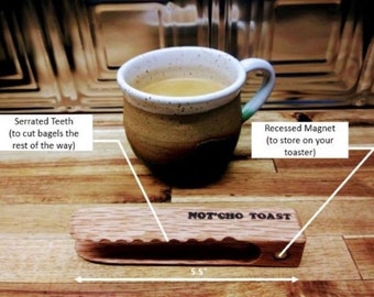 May include: Wooden bagel cutter with serrated teeth for cutting bagels. The cutter has a recessed magnet for storing on a toaster. The cutter is 5.5 inches long and has the text "NOT'CHO TOAST" engraved on it.