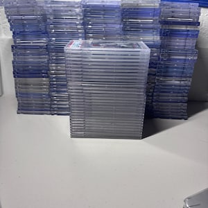 Puede incluir: Montones de protectores de tarjetas de plástico transparente, algunos con tarjetas, están dispuestos sobre una superficie blanca. Los protectores rectangulares parecen ser fundas de tarjetas clasificadas.