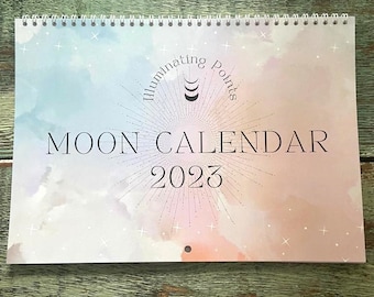 May include: A white and pink moon calendar for 2023 with the text "Illuminating Points Moon Calendar 2023" and a stylized moon and stars design.