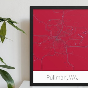 May include: A framed map of Pullman, WA. The map is printed on a red background with blue lines representing streets. The city name is printed in white at the bottom of the map.