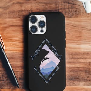 May include: Black phone case featuring a mountain climbing graphic. The design includes a silhouette of a climber on a rock face, with a backdrop of mountains and a geometric frame. The case is shown on a wooden surface.