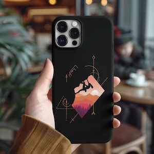 May include: Black phone case featuring a mountain climbing design. The case has a geometric design with a climber silhouette, mountains, and a sunset color scheme. The case is held in a person's hand.