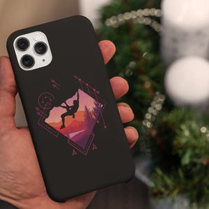 May include: Black phone case featuring a geometric design with a mountain climber silhouette against a sunset backdrop. The case has a matte finish and a camera cutout. The design includes geometric shapes and arrows.