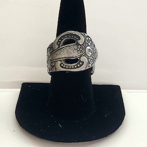 May include: A silver ring made from a repurposed spoon with an ornate floral design.