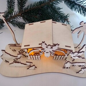 Pu&ograve; includere: Un presepe in legno con una stalla illuminata, una palma e figure di un angelo, un pastore e animali. La scena &egrave; realizzata in legno chiaro e ha un aspetto rustico e artigianale.
