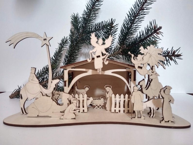 Pu&ograve; includere: Un presepe in legno con una stella, un angelo e le figure dei tre re magi, Maria, Giuseppe e il bambino Ges&ugrave;. La scena &egrave; ambientata in una stalla con una recinzione e una palma.