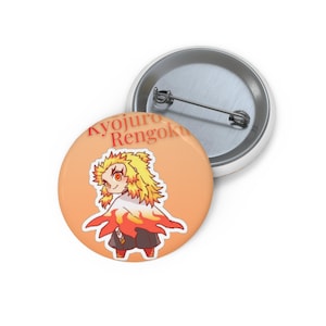 Könnte beinhalten: Ein runder Ansteckbutton mit einer Illustration von Kyojuro Rengoku im Chibi-Stil, mit stacheligem gelb-rotem Haar und einem Umhang mit Flammenmuster. Der Hintergrund ist hellorange und trägt den roten Schriftzug Kyojuro Rengoku.