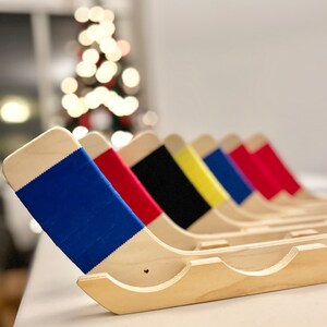 Puede incluir: Un conjunto de seis soportes de palo de hockey de madera con detalles de cinta de colores. Los soportes est&aacute;n dispuestos en fila, con el soporte de cinta azul en primer plano. Los soportes est&aacute;n hechos de madera natural y tienen un dise&ntilde;o simple y elegante.