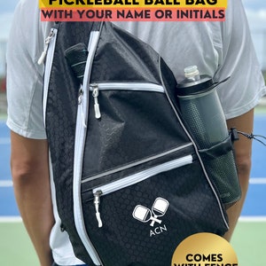 May include: A black pickleball bag with white accents and a mesh water bottle holder. The bag has a zippered compartment for paddles and a fence hook. The bag is worn by a person on a tennis court. The text on the bag reads "CUSTOM CONVERTIBLE PICKLEBALL BALL BAG WITH YOUR NAME OR INITIALS" and "ACN". The text on the gold circle reads "COMES WITH FENCE HOOK". The text at the bottom reads "ETSY: CATCHCATCHCREATIONS".