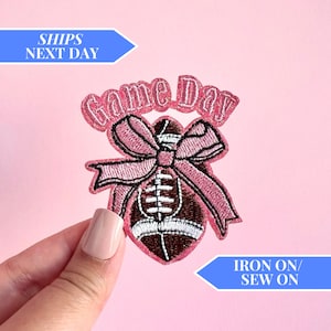 May include: Pink iron-on or sew-on patch with a football and a bow. The patch says "Game Day".