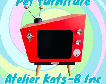 May include: Red retro-style TV-shaped pet furniture with black legs and a black interior. The furniture has a silver star design and silver knobs. The text "Atelier Kats-B Inc" is printed on the front.