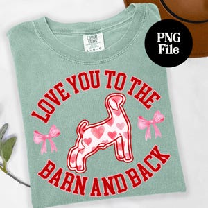 May include: A light green t-shirt with the text "LOVE YOU TO THE BARN AND BACK" in red. A goat illustration with heart patterns is in the center, with pink bows on each side. The shirt has a "COMFORT COLORS" tag.