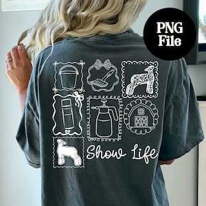 May include: Dark gray t-shirt with white line drawings of farm-related items, including a bucket, a bow, a sheep, a spray bottle, a barn, and a sheep. The words "Show Life" are written in a script font below the drawings.