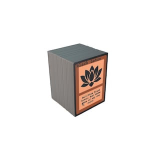 Op de afbeelding: Een stapel ruilkaarten met een zwart lotusbloemontwerp. De kaart heeft een zwarte rand en een perzikkleurige achtergrond. De tekst "Black Lotus" staat bovenaan, met instructies eronder.
