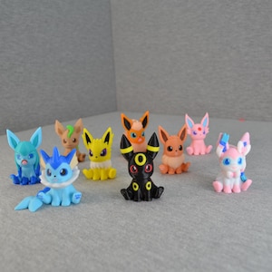 Könnte beinhalten: Eine Sammlung farbenfroher Figuren verschiedener Pokémon-Charaktere. Die Figuren sind in verschiedenen Posen und Farben, darunter Blau, Gelb, Orange, Rosa und Schwarz. Die Figuren sind klein und scheinen aus Kunststoff zu sein.