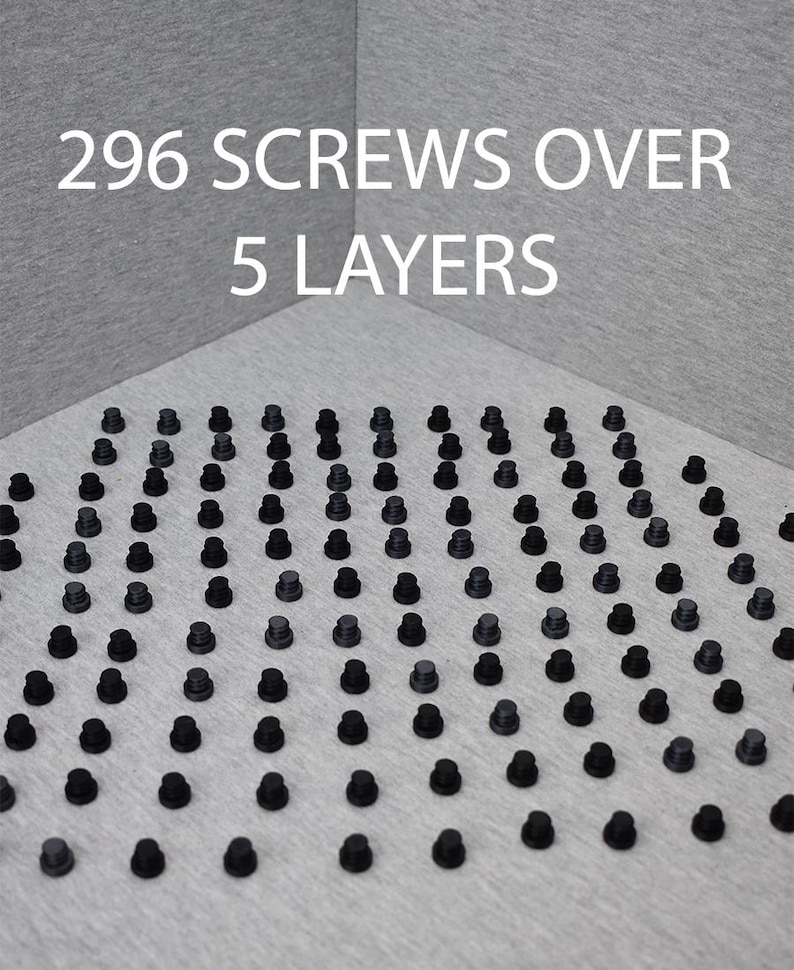 Op de afbeelding: Een close-up van 296 zwarte schroeven die in een patroon zijn gerangschikt op een grijs oppervlak. De tekst "296 SCREWS OVER 5 LAYERS" is zichtbaar bovenaan de afbeelding.