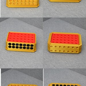 Op de afbeelding: Een gouden plastic opbergdoos met een rood deksel en zwarte cirkels. De doos heeft een raster van gaten aan de boven- en onderkant. De doos is leeg.