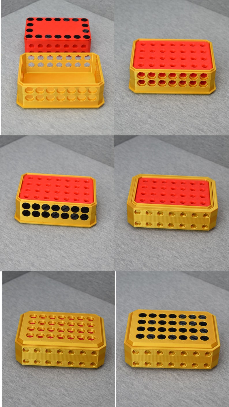 Op de afbeelding: Een gouden plastic opbergdoos met een rood deksel en zwarte cirkels. De doos heeft een raster van gaten aan de boven- en onderkant. De doos is leeg.