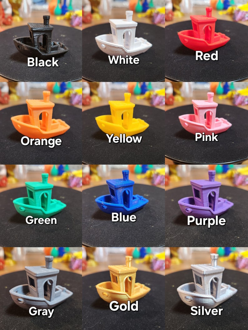 Op de afbeelding: Een set van 12 miniatuur speelgoedbootjes in verschillende kleuren, waaronder zwart, wit, rood, oranje, geel, roze, groen, blauw, paars, grijs, goud en zilver. Elk bootje heeft een kleine schoorsteen en een eenvoudig ontwerp.