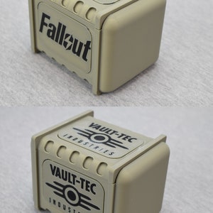 以下が含まれることがあります： 前面に黒い「Fallout」ロゴ、側面に黒い「Vault-Tec Industries」ロゴが付いたベージュの箱