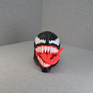 May include: A black Venom bust with white eyes and teeth, and a red tongue. The bust is a detailed representation of the Marvel Comics character, with a menacing expression.