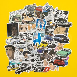 May include: A selection of Initial D anime stickers on a yellow backdrop. The stickers depict characters, cars, and Japanese text. Some stickers include the phrases "LONELY DRIVER", "NIGHTKIDS", and "INITIAL 頭文字D".