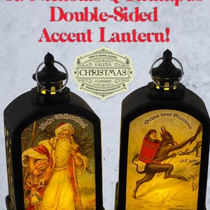 May include: Black double-sided accent lantern featuring St. Nicholas and Krampus illustrations. The lantern has a metal loop for hanging and includes text that reads "St. Nicholas & Krampus Double-Sided Accent Lantern!" and "Galena Christmas Company."
