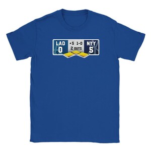 May include: Royal blue t-shirt featuring a baseball scoreboard graphic. The graphic displays the score of a baseball game between LAD and NYY, with the score being 0-5. The shirt also shows 2 outs.