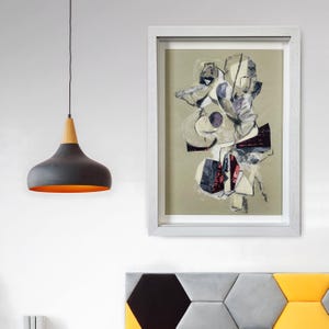 May include: Abstract art print in a white frame. The artwork features a collage of shapes in white, grey, and red on a beige background. A black pendant light with a wooden top and orange interior hangs to the left.