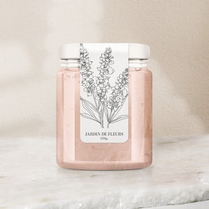 May include: A clear glass jar with a white lid and a label that says "JARDIN DE FLEURS 350g". The label has a black and white line drawing of flowers.