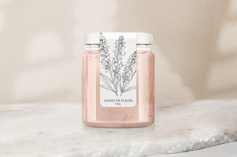 May include: A clear glass jar with a white lid and a label that says "JARDIN DE FLEURS 350g". The label has a black and white line drawing of flowers.