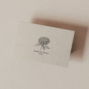 May include: A white card with a black and white illustration of a flower and the text "Jardin de Fleurs Organic".
