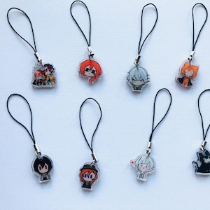Peut inclure: Ensemble de huit breloques de personnages de style anime avec des lanières noires. Chaque breloque présente un design de personnage différent, avec des couleurs de cheveux et des tenues variées. Les breloques sont en acrylique transparent et sont fixées à des cordons noirs.