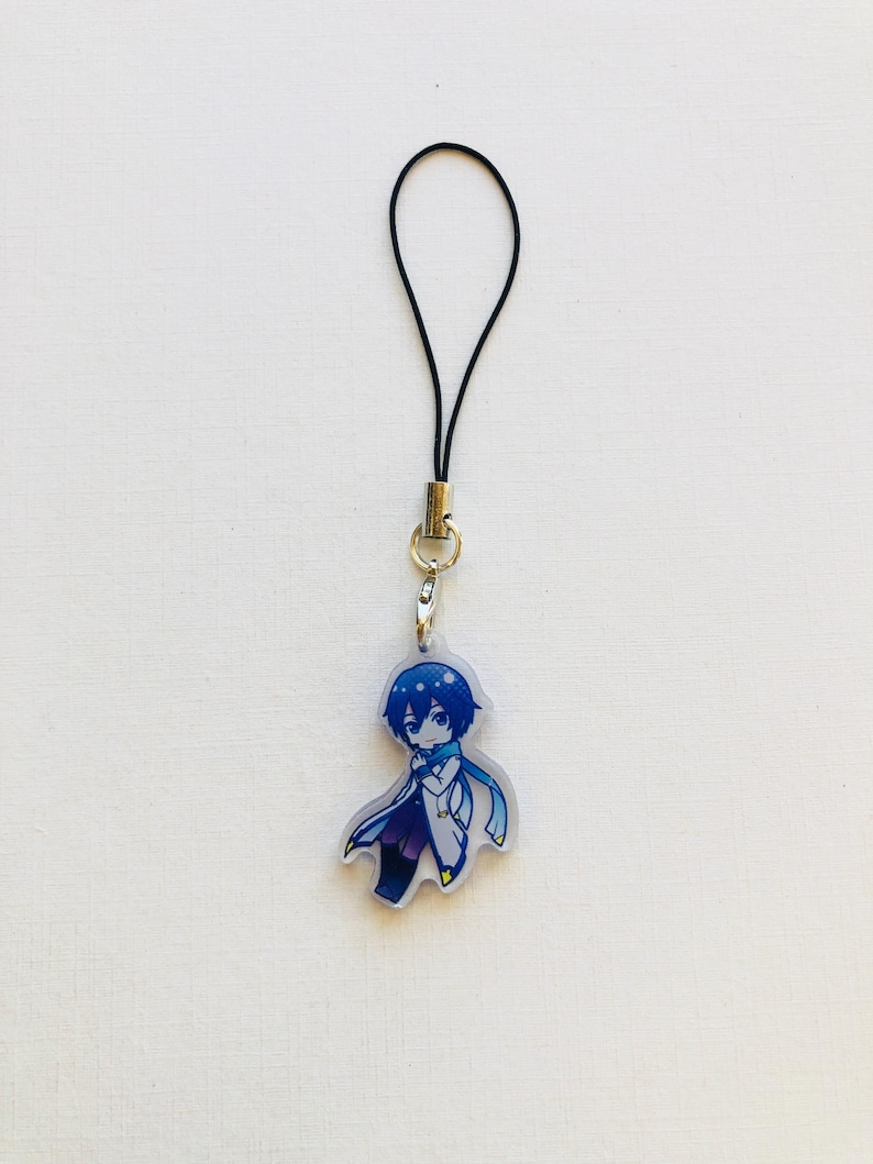 Peut inclure: Un porte-cl&eacute;s de style anime bleu et blanc repr&eacute;sentant un personnage aux cheveux bleus et une &eacute;charpe. Le porte-cl&eacute;s est attach&eacute; &agrave; un cordon noir avec un fermoir dor&eacute;. Le personnage porte un manteau blanc et un pantalon violet.