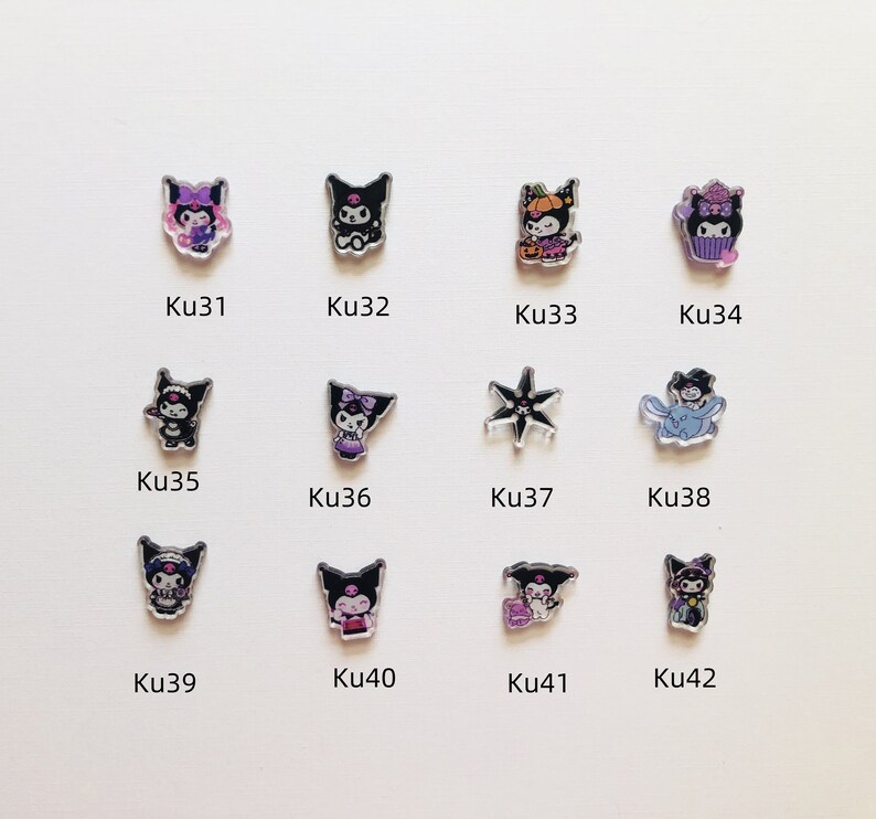 Op de afbeelding: Een verzameling van twaalf acryl bedels met verschillende stripfiguren in verschillende poses en outfits. De bedels zijn in verschillende kleuren, waaronder zwart, paars en oranje, en zijn gelabeld met de codes Ku31 tot Ku42.
