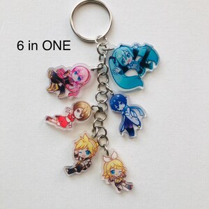 Peut inclure: Un porte-cl&eacute;s avec six breloques de personnages de style anime. Chaque breloque repr&eacute;sente un personnage diff&eacute;rent avec des couleurs de cheveux et de v&ecirc;tements distinctes. Les breloques sont reli&eacute;es par une cha&icirc;ne argent&eacute;e et un porte-cl&eacute;s. Le texte "6 in ONE" est imprim&eacute; en haut &agrave; gauche.