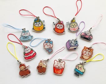 Puede incluir: Una colección de 12 llaveros con dijes coloridos que representan personajes de dibujos animados. Los dijes están hechos de acrílico transparente y presentan varios diseños, incluyendo animales, comida y amuletos de la suerte japoneses tradicionales. Los llaveros están unidos a cordones de colores.