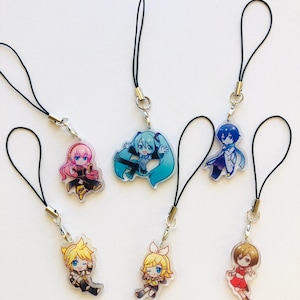 Peut inclure: Six breloques de personnages de style anime. Chaque breloque pr&eacute;sente un design diff&eacute;rent avec des couleurs vives et est attach&eacute;e &agrave; un cordon noir. Les breloques sont en acrylique transparent.