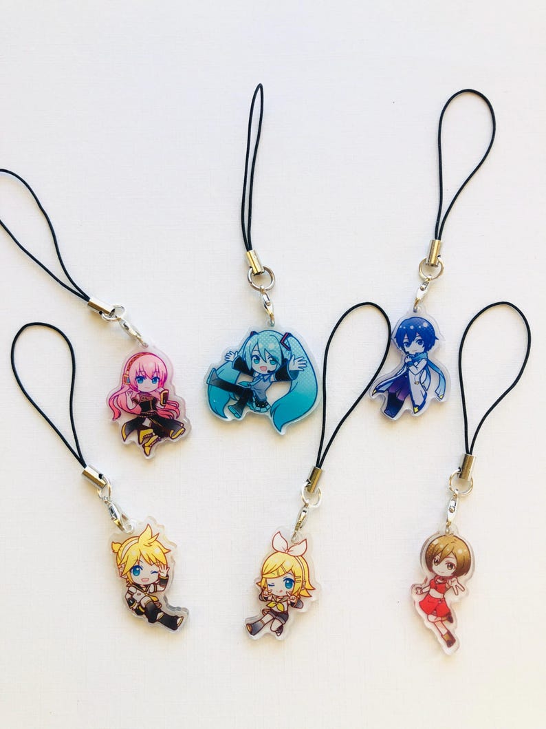 Peut inclure: Six breloques de personnages de style anime. Chaque breloque pr&eacute;sente un design diff&eacute;rent avec des couleurs vives et est attach&eacute;e &agrave; un cordon noir. Les breloques sont en acrylique transparent.