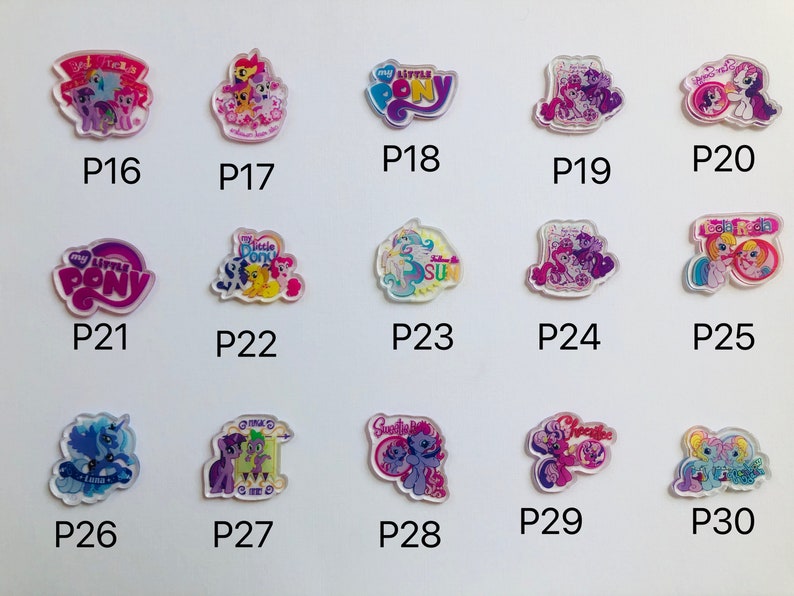 May include: A set of 10 colorful, clear plastic charms featuring My Little Pony characters. The charms are arranged in a grid pattern on a white background. Each charm has a different character and design, including a pink pony with a rainbow mane, a purple pony with a blue mane, and a yellow pony with a pink mane.