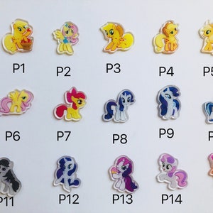May include: A set of 15 colorful cartoon pony charms, each with a different design and pose. The charms are made of clear plastic with a printed image on the front. The charms are numbered P1 through P15.