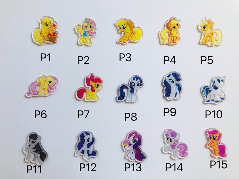 May include: A set of 15 colorful cartoon pony charms, each with a different design and pose. The charms are made of clear plastic with a printed image on the front. The charms are numbered P1 through P15.