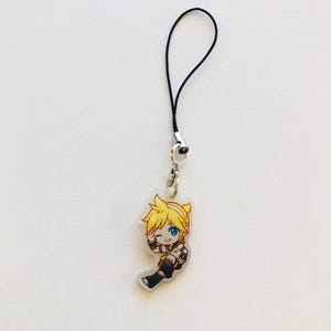 Peut inclure: Un charm en acrylique transparent repr&eacute;sentant un personnage de dessin anim&eacute; aux cheveux jaunes et aux yeux bleus, faisant un clin d'&oelig;il. Le charm est attach&eacute; &agrave; un cordon noir avec un fermoir argent&eacute;. Le personnage porte une tenue noire et blanche.