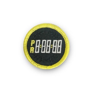May include: A black and yellow round embroidered patch with the text "PA" and a digital clock displaying "88:88".